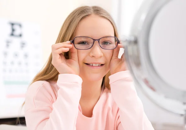 Young little girl trying glasses at the optician — Stock Photo, Image