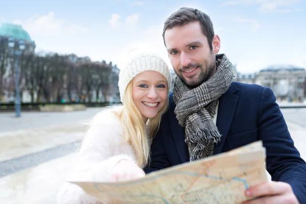 Couple of young attractive tourists watching map — Stock Photo, Image