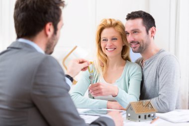 Emlakçı yeni ev anahtarları için genç çift sunar.