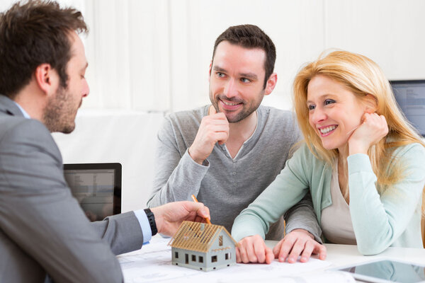 Агент по недвижимости представляет молодому человеку проект по миниатюрному дому
 