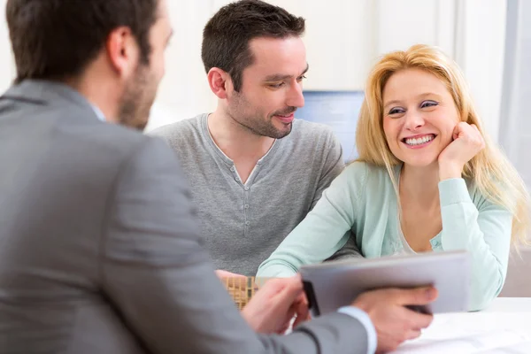 Onroerende goederenagent huidige project op tafel aan een jong koppel — Stockfoto