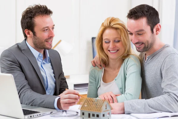 Real estate agent present project on miniature house to a young — Stock Photo, Image