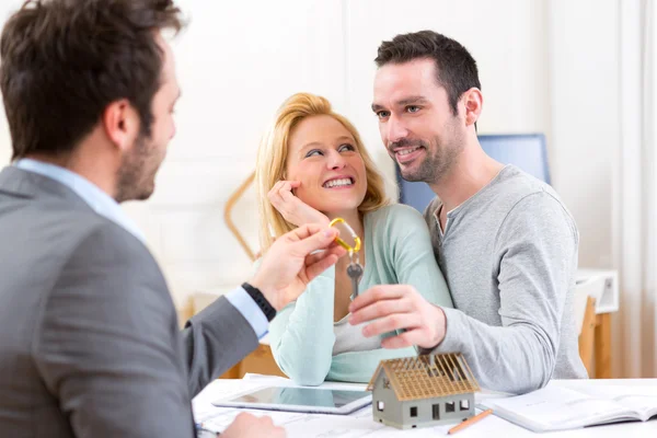 Immobilienmakler übergibt Schlüssel für neues Haus an junges Paar — Stockfoto