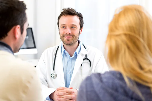 Jonge aantrekkelijke dokter adviseren een jong koppel van patiënten — Stockfoto