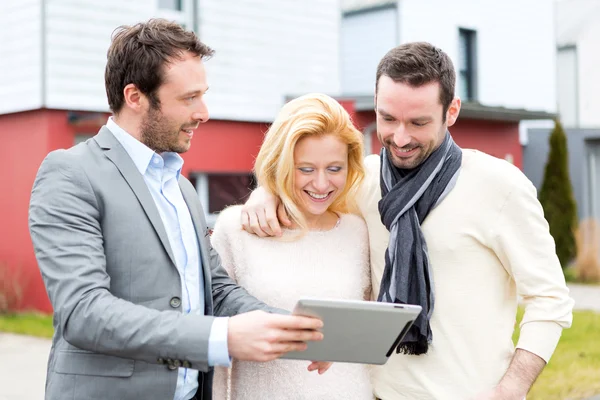 Real estate agent and a young couple in front of their next home — Stock Photo, Image