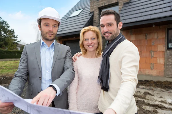 Real estate agent and a young couple in front of future home — Stock Photo, Image