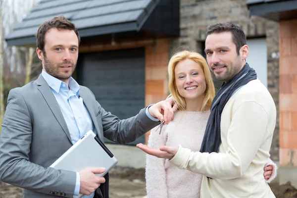 Real estate agent delivers keys to young atractive couple — Stock Photo, Image