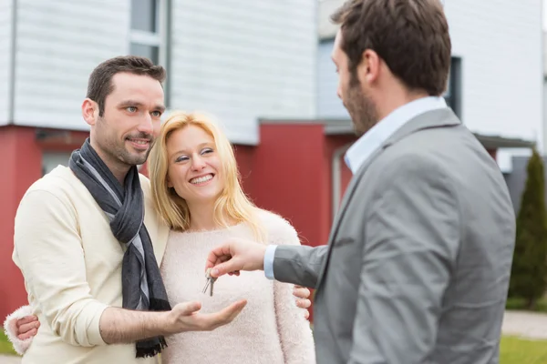 Agente de bienes raíces entrega llaves a joven pareja atractiva — Foto de Stock
