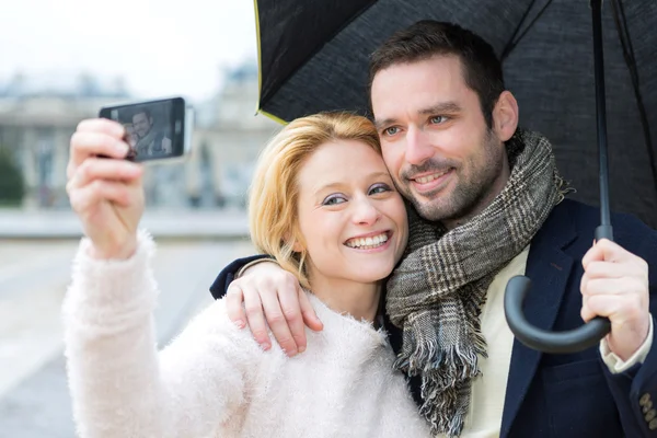 Mladý pár na svátky za deště s selfie — Stock fotografie