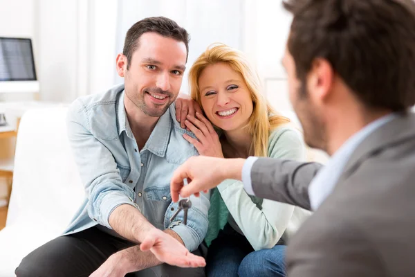 Real estate agent delivers keys of new house to young couple Royalty Free Stock Photos