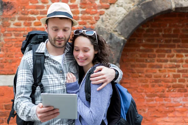 Jeune couple de touristes utilisant tablette pour visiter la ville — Photo