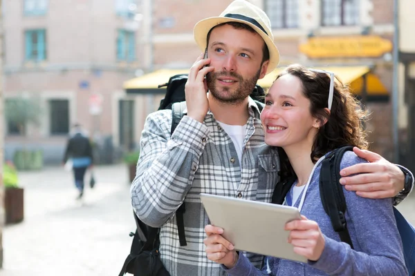 Casal de turistas atraentes usando tablet e smartphone — Fotografia de Stock