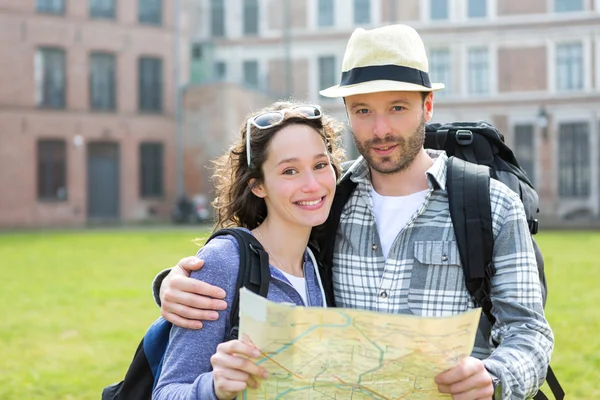 Couple of young attractive tourists watching map — Stock Photo, Image