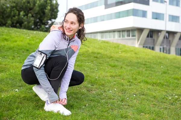 Junge attraktive Frau bindet Schnürsenkel vor einer Laufeinheit — Stockfoto