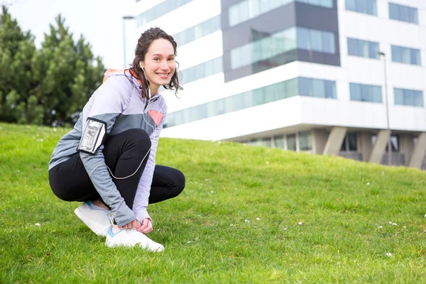 Jeune femme séduisante attachant lacets avant une session de course — Photo