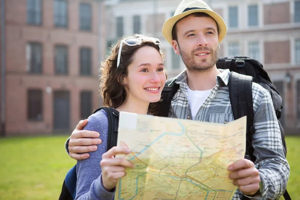 Couple of young attractive tourists watching map — Stock Photo, Image