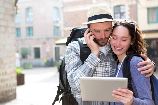 Pareja de turistas atractivos usando tableta y teléfono inteligente —  Fotos de Stock