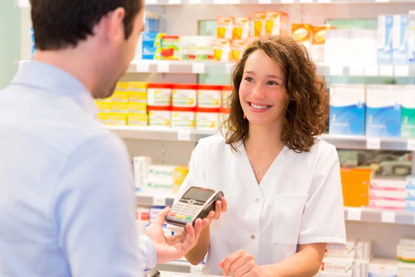 Attractive pharmacist taking healt insurance card — Stock Photo, Image