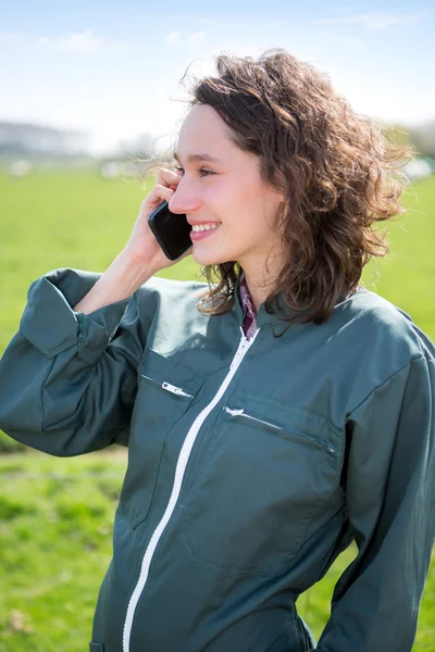 Joven agricultor atractivo en un campo usando teléfono móvil — Foto de Stock