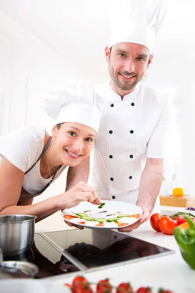 Jovem chef treinando uma jovem garota atraente para cozinhar — Fotografia de Stock