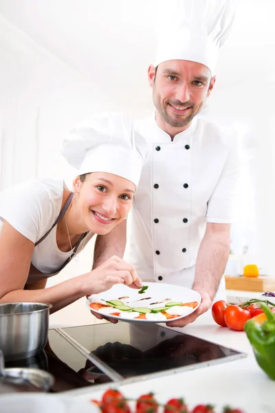 Joven chef de formación de una joven chica atractiva para cocinar — Foto de Stock