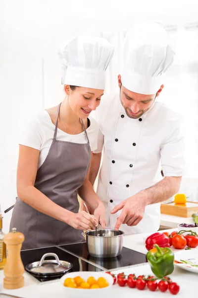Молодий шеф-кухар навчає молоду привабливу дівчину готувати — стокове фото