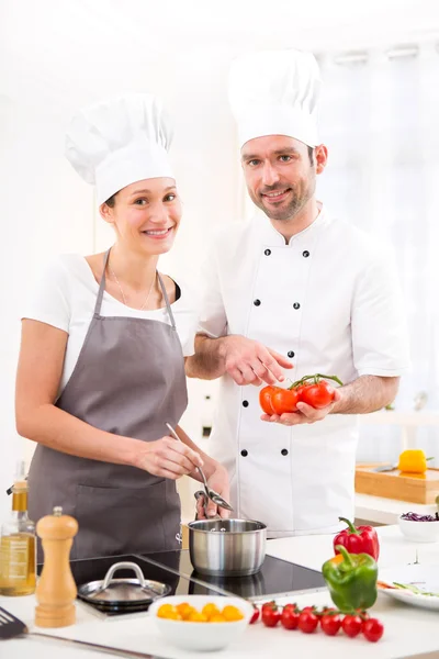 Jovem chef treinando uma jovem garota atraente para cozinhar — Fotografia de Stock