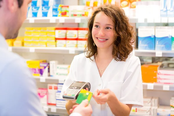 Attractive pharmacist taking healt insurance card — Stock Photo, Image