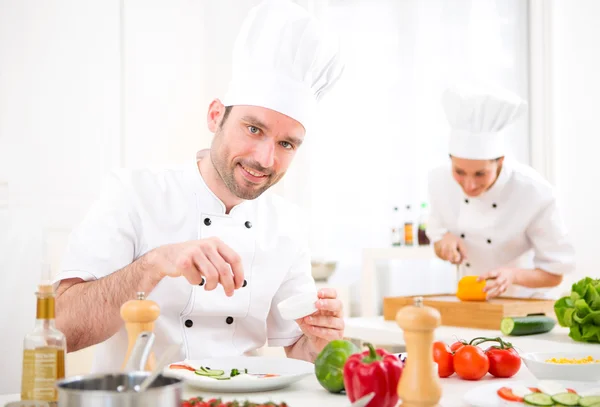 Jovem chef profissional atraente cozinhar em sua cozinha — Fotografia de Stock