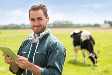 Nézd a tehenek legelőn egy vonzó fiatal mezőgazdasági termelőçekici genç bir çiftçi bir arazide inek ile portresi