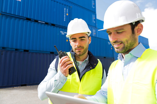 Dock worker and supervisor checking containers data on tablet