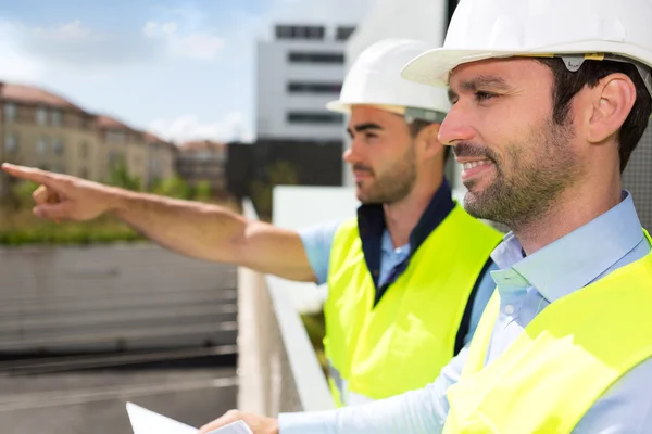 Arbetare och arkitekt tittar några detaljer på en konstruktion — Stockfoto