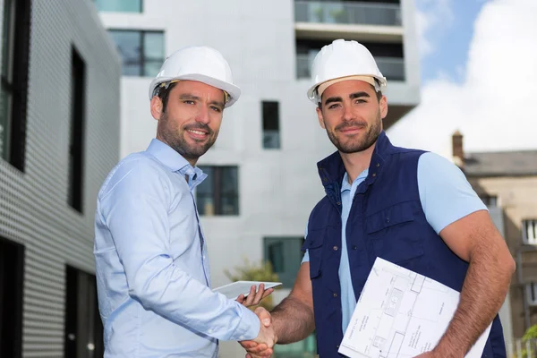 Architekt a pracovníků handshaking na staveništi — Stock fotografie
