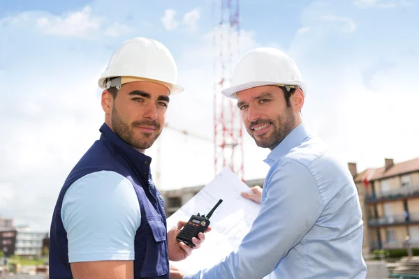 Ingenieur en werknemer kijken blauwdruk op de bouwplaats — Stockfoto