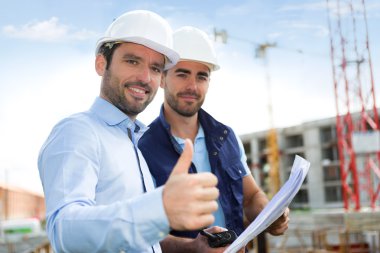 mühendis ve işçi blueprint inşaat sitesinde izliyor 
