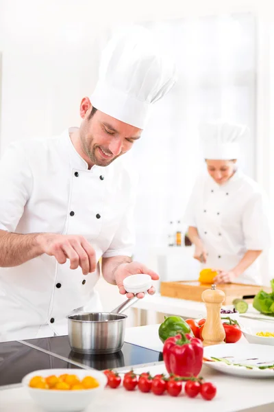 Weergave van een jonge aantrekkelijke professionele chef-kok koken in zijn keuken — ストック写真