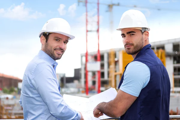 Engineer and worker checking plan on construction site — Stock Photo, Image