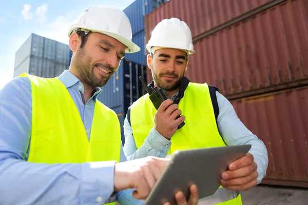 Dock worker and supervisor checking containers data on tablet — 스톡 사진