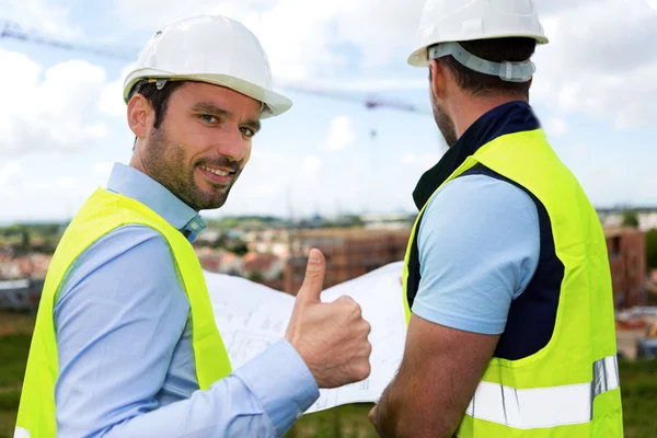 Ingenjör och arbetstagaren tittar på ritningen på byggarbetsplats — Stockfoto