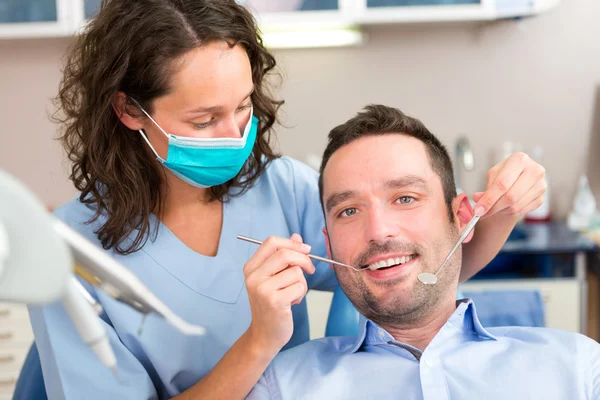 Jovem homem atraente sendo curado por um dentista — Fotografia de Stock