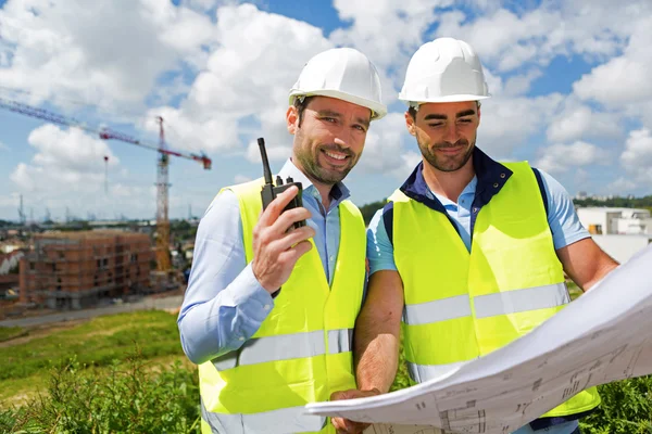 Ingeniero y trabajador viendo el plano en el sitio de construcción — Foto de Stock