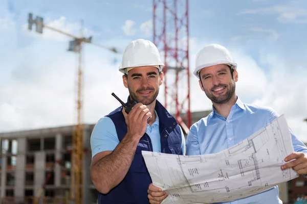 Engineer and worker watching blueprint on construction site — Stock Photo, Image