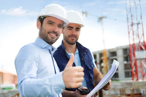 Engineer and worker watching blueprint on construction site — Stock Photo, Image