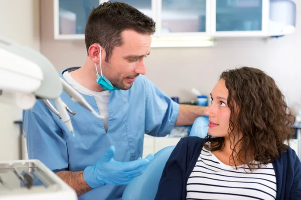 Junger attraktiver Zahnarzt erklärt einem Patienten seine Arbeit — Stockfoto