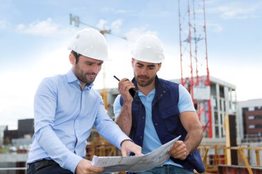 mühendis ve işçi blueprint inşaat sitesinde izliyor 