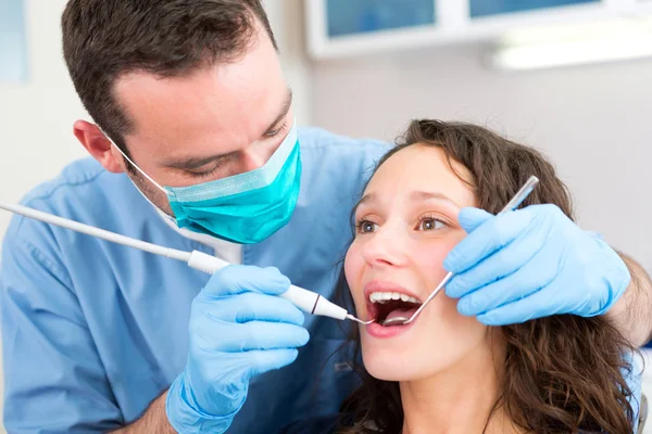 Young attractive woman being cured by a dentist — Stock Photo, Image