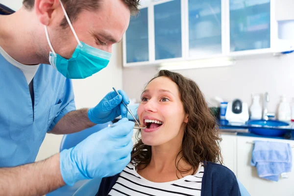 Joven mujer atractiva siendo curada por un dentista — Foto de Stock