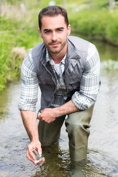 Biologist take a sample in a river in order to do some test — Stock Photo, Image