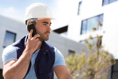 Yong çekici çalışan cep telefonuyla bir inşaat otur