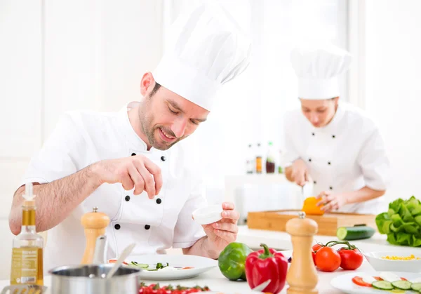 Jovem chef profissional atraente cozinhar em sua cozinha — Fotografia de Stock